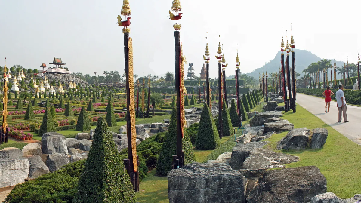 Long garden road beside formal planting and decorative poles at Nong Nooch
