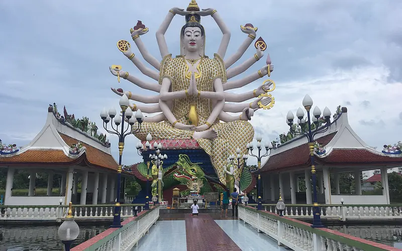 Guanyin figure, bridge and waterside temple buildings at Wat Plai Laem