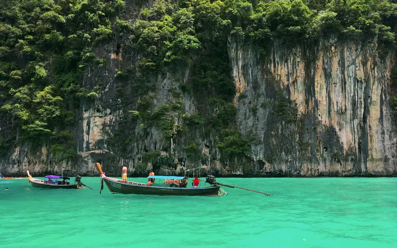 Longtail boats beneath limestone cliffs in Pileh Lagoon at Phi Phi Leh